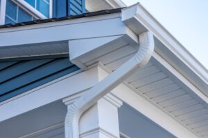 Colonial white gutter guard system, fascia, drip edge, soffit providing ventilation to the attic, with pacific blue vinyl horizontal siding at a luxury American single family home neighborhood USA; gutter maintenance; gutter replacement; gutter cleaning; gutter repair