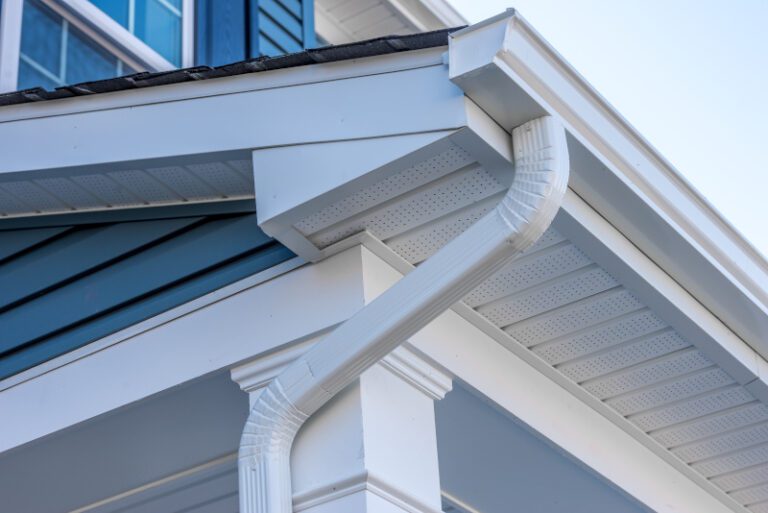 Colonial white gutter guard system, fascia, drip edge, soffit providing ventilation to the attic, with pacific blue vinyl horizontal siding at a luxury American single family home neighborhood USA
