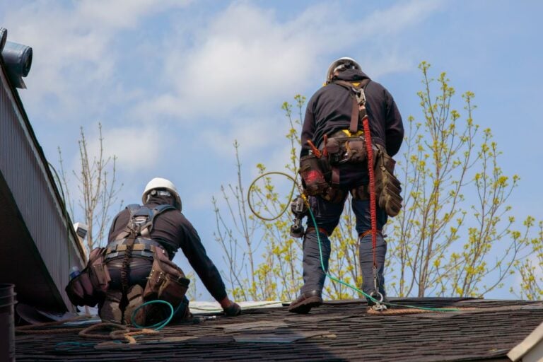 two roofers repairing roof