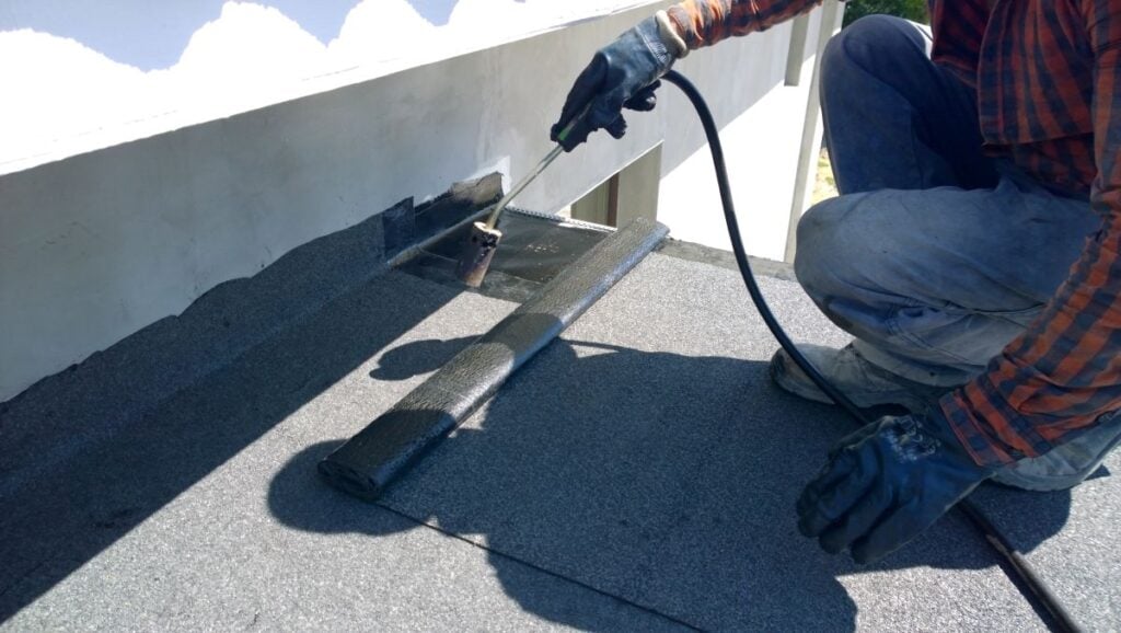 Roofer preparing part of bitumen roofing felt roll