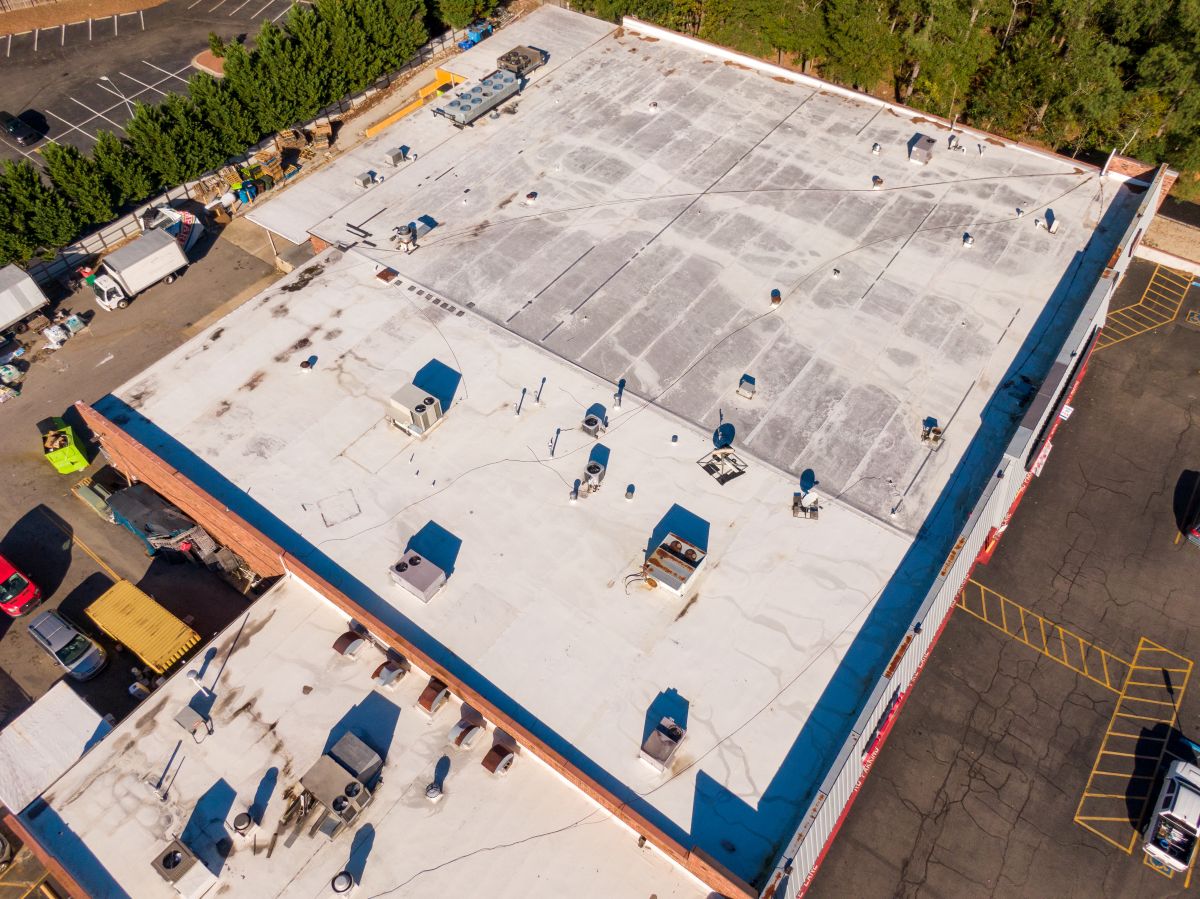 Sunny Daytime Aerial Drone Images of an Old Weathered TPO Roof on a Commercial Building