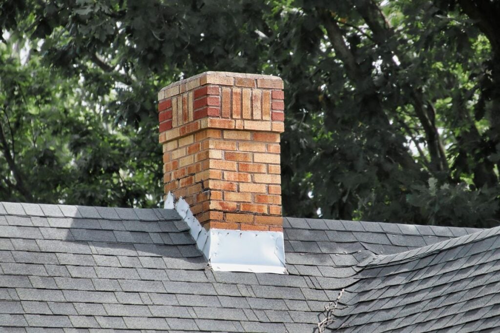chimney flashing repair charcoal shingles roof orange brick wall