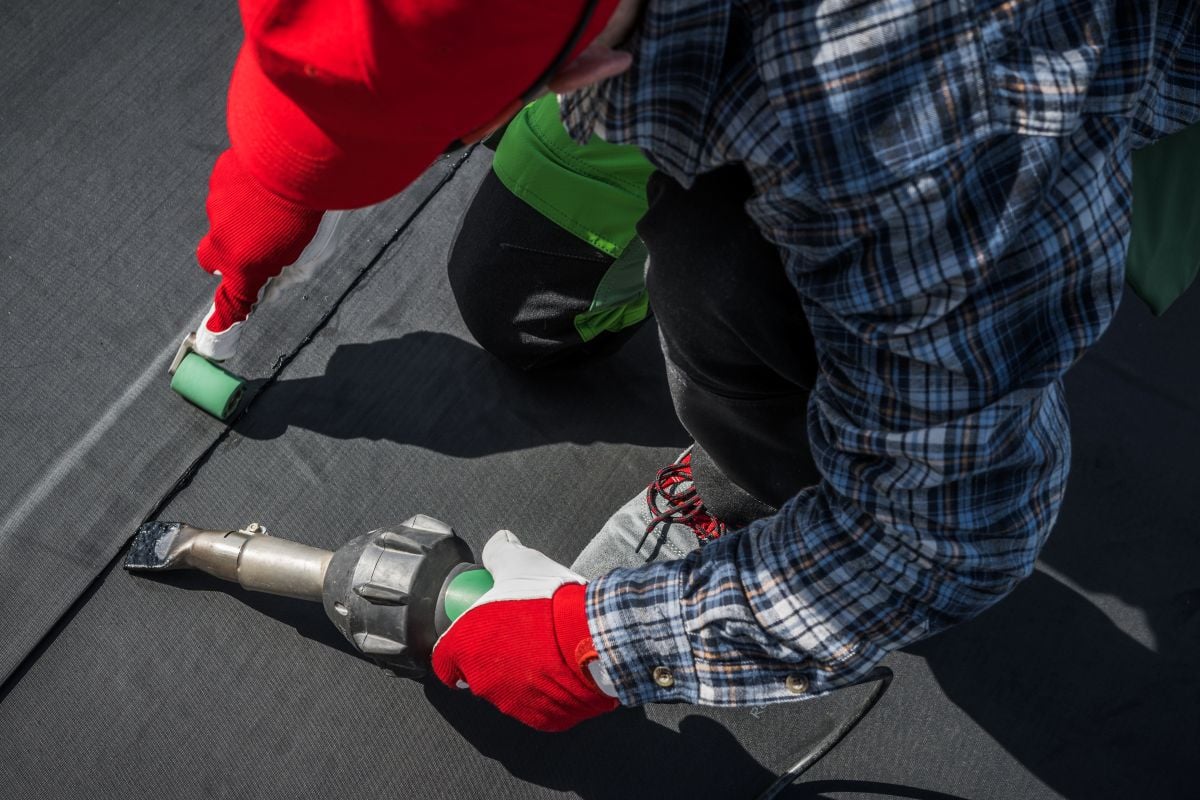 epdm roof worker installing using roller