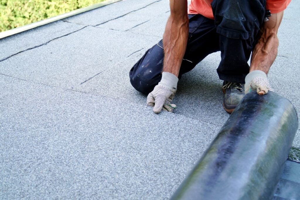 flat roof insulation worker using gloves to unfold roll