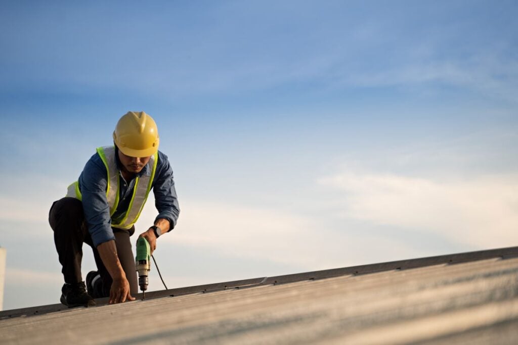 roof warranty workers repairing metal on top