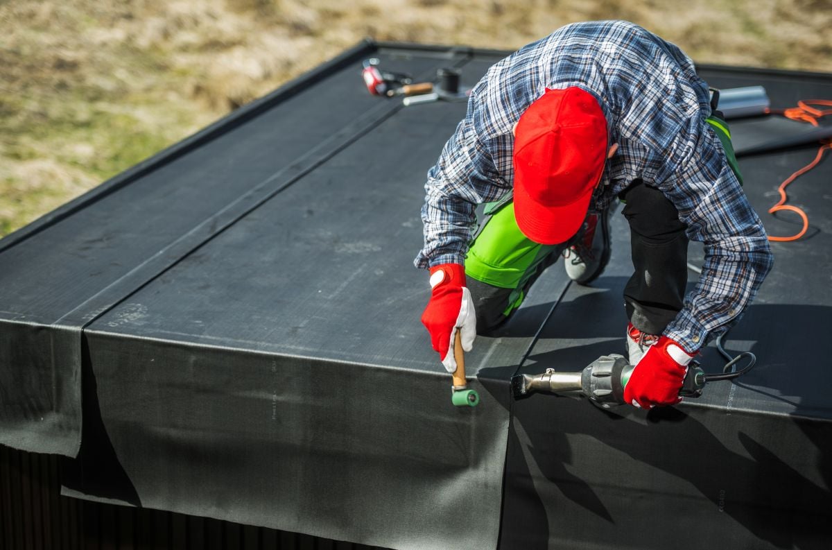 rubber roof repair worker using roller and heat gun house