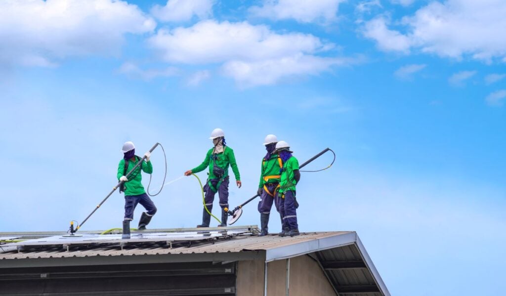 commercial roof cleaning worker using hose to clean