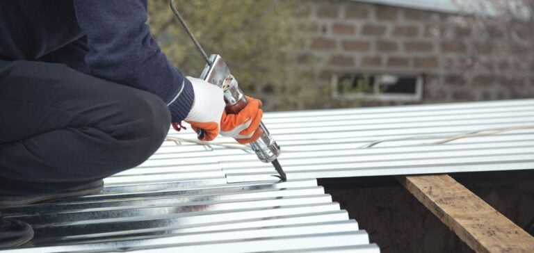 roof sealant worker applying black material on metallic roof