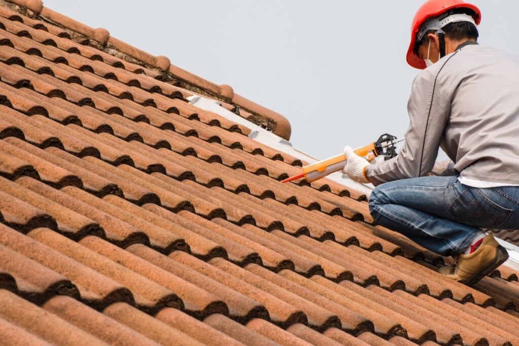 roof sealant worker applying meterial orance ceramic tiles