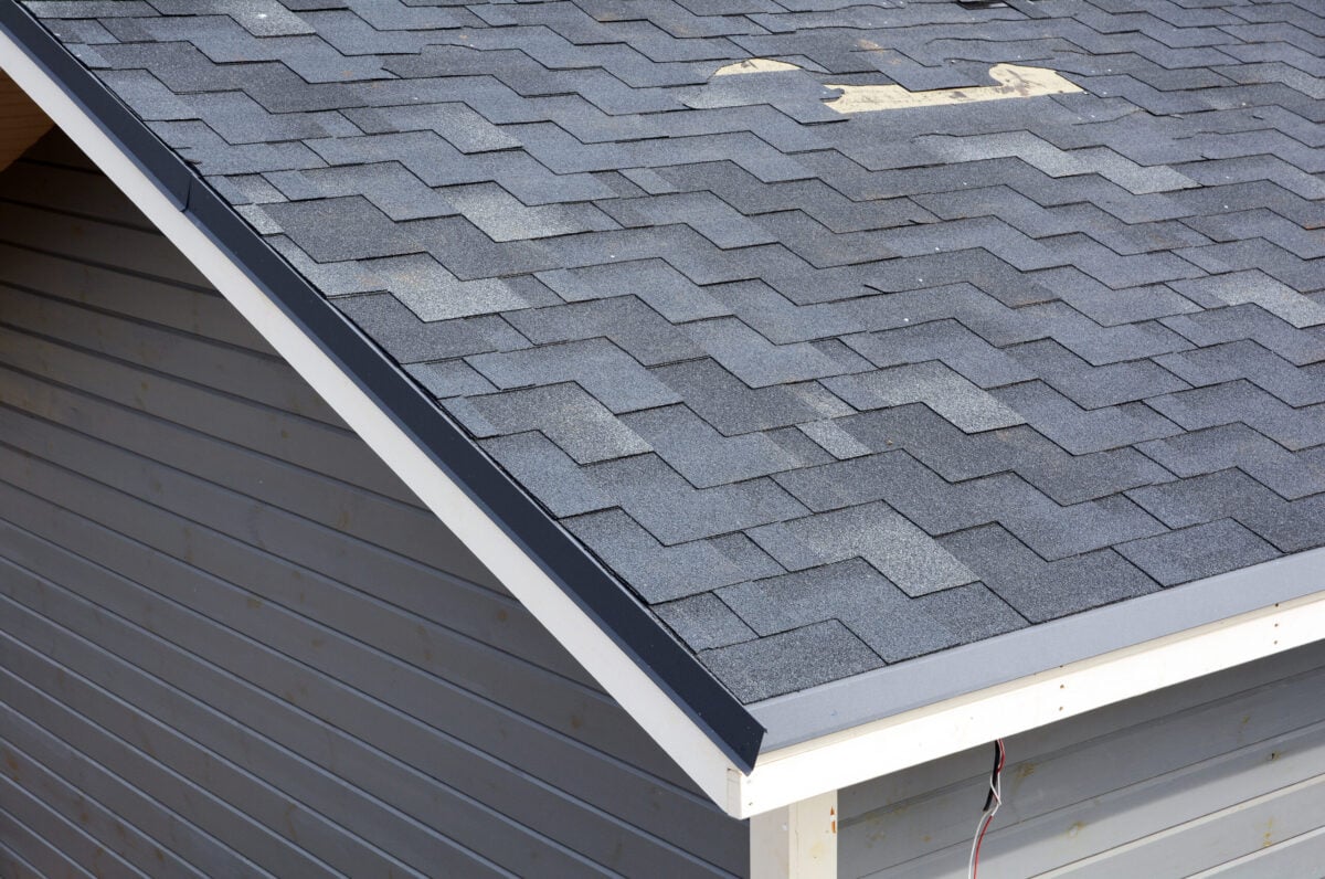 wind damaged shingles A close up view of shingles a roof damage. Roof Shingles - Roofing.