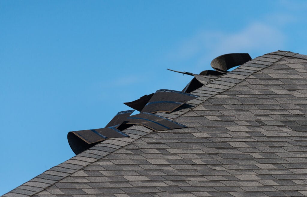 wind damaged shingles lifting from roof after wind storm