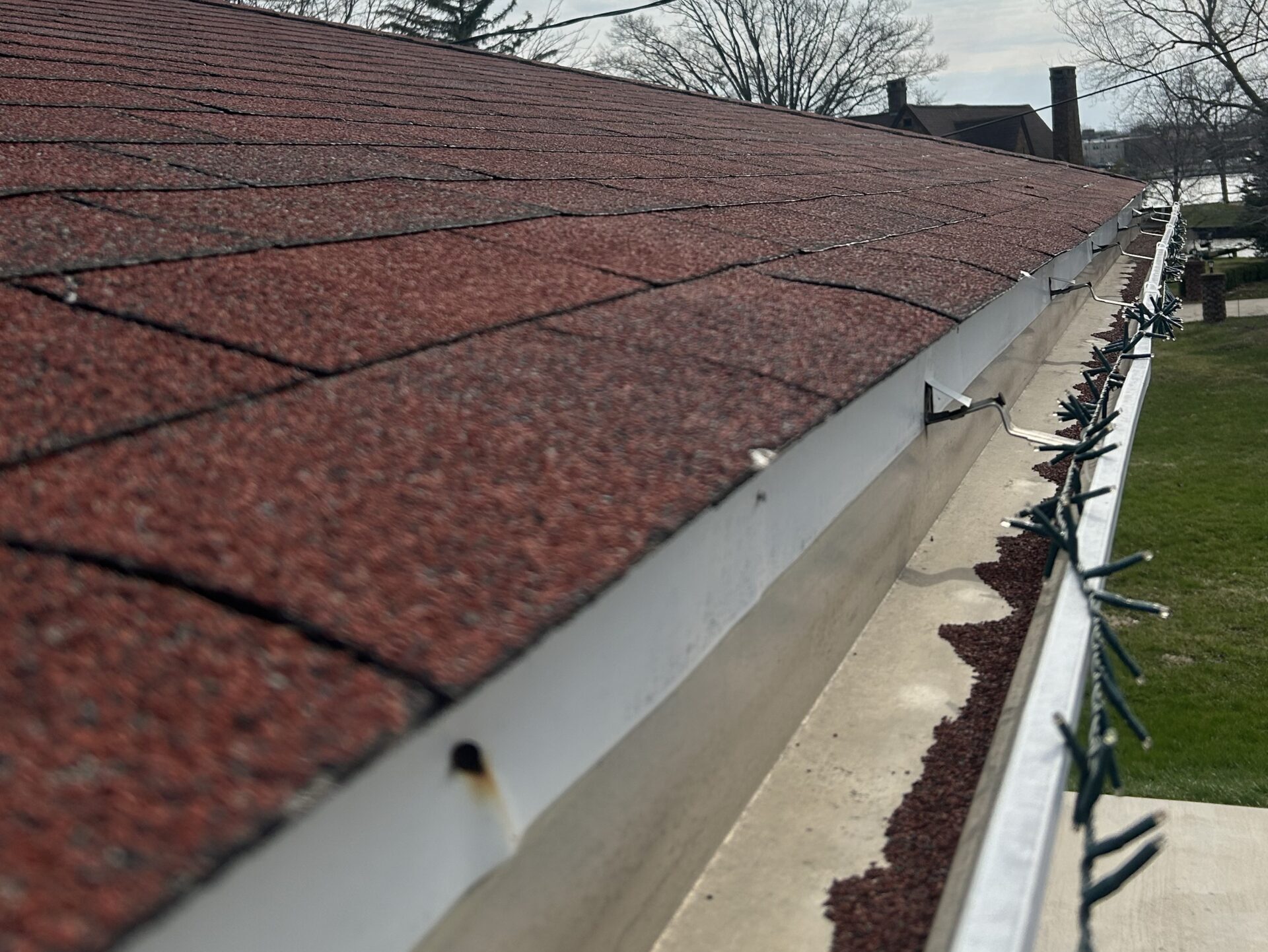 seamless vs sectional gutters brown shingles closeup dirty water system