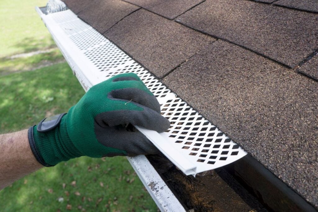 gutter guard types hand using glove holding white guard