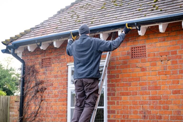 seamless vs sectional gutters guy using gloves installing new water system