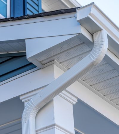 Colonial white gutter guard system, fascia, drip edge, soffit providing ventilation to the attic, with pacific blue vinyl horizontal siding at a luxury American single family home neighborhood USA; gutter maintenance; gutter replacement; gutter cleaning; gutter repair