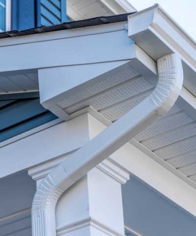 Colonial white gutter guard system, fascia, drip edge, soffit providing ventilation to the attic, with pacific blue vinyl horizontal siding at a luxury American single family home neighborhood USA; gutter maintenance; gutter replacement; gutter cleaning; gutter repair